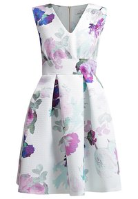 Robe florale avec un tissu matelassé blanc, décolleté en V, taille cintrée et jupe évasée ; motifs floraux violets et verts prononcés.