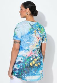 T-shirt z nadrukiem graficznym w kolorze niebieskim, z kolorowymi kwiatowymi i abstrakcyjnymi wzorami. Krótkie rękawy, luźny krój, gładka tekstura i okrągły dekolt.