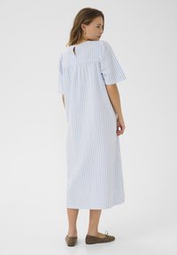 Modra in bela črtasta dolga obleka s kratkimi rokavi, podrobnostjo v obliki ključavnice na hrbtu, sproščenim krojem in mehkimi, teksturiranimi materiali.