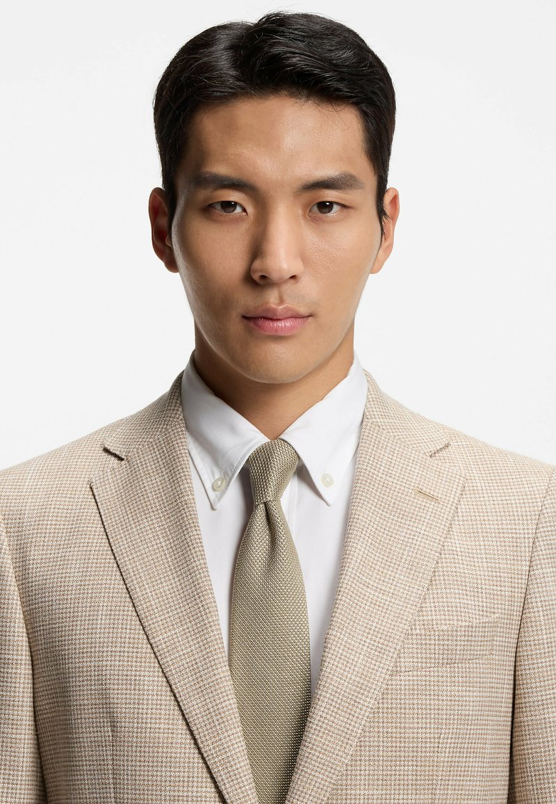 Giacca da completo a quadri beige con camicia bianca con colletto e cravatta grigio chiaro. Tessuto liscio, vestibilità sartoriale e dettagli netti del rever.