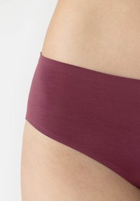 Slip bikini in tessuto bordeaux con una texture liscia e una vita bassa, caratterizzato da un design senza cuciture per comfort e minima visibilità.