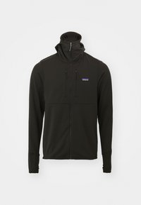 Črna zip-up jakna z visokim ovratnikom, mehkega haptike, dolgimi rokavi in nastavljivimi vrvicami. Ima manjši logotip na prsih.