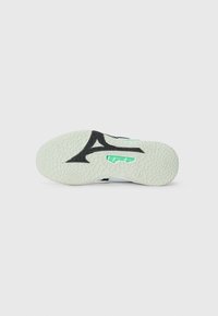 Sole of a sneaker with a textured, white rubber base. Features a black geometric design and a green accent on the side.