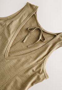 Top sans manches vert olive avec col en V et un détail de lien dans le dos, en tissu doux et texturé avec des coutures visibles.