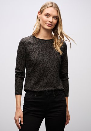 Top nero a maniche lunghe con motivo a stampa leopardo, realizzato in tessuto morbido, dotato di scollatura rotonda e vestibilità aderente, abbinato a jeans scuri.