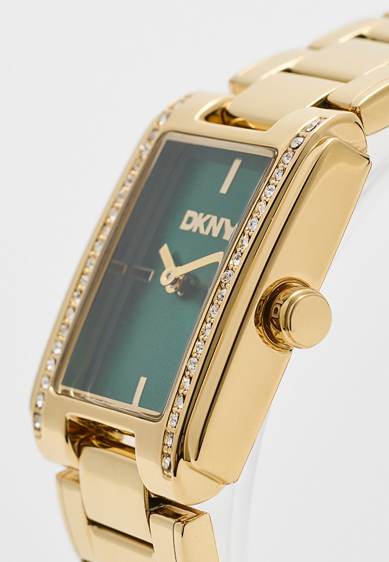 Goldfarbener DKNY-Uhr mit rechteckiger Form, grünem Zifferblatt, Kristallakzenten entlang der Lünette und einer Krone an der Seite.