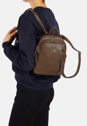 Zaino in pelle marrone con forma strutturata, dotato di manico superiore, tracolla regolabile e scomparto con zip.