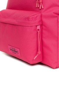 Zaino Eastpak rosa acceso con finitura testurizzata, dotato di una tasca frontale e chiusura con coulisse per una maggiore funzionalità.