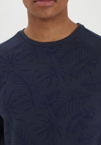 Felpa blu navy con un motivo testurizzato di felci. Presenta un collo rotondo e maniche raglan, realizzata in morbido cotone.