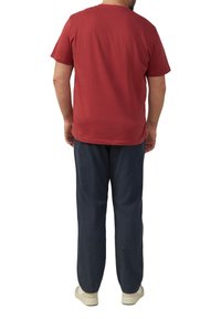 Camiseta de algodón roja con cuello redondo, combinada con pantalones tejidos azul marino. Costuras visibles, corte relajado y zapatos neutros.