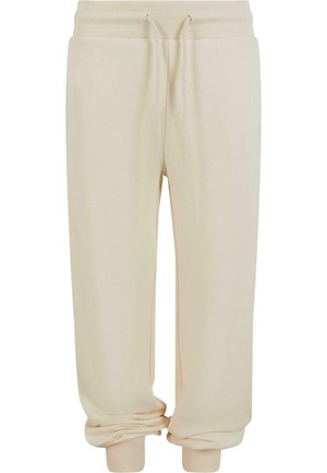 Pantalon de survêtement beige avec taille élastique côtelée, cordon de serrage, poches avant profondes et poignets côtelés aux chevilles.