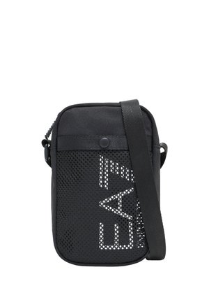 Pequeño bolso bandolera negro con bolsillo frontal de malla y texto parcial blanco, correa ajustable y cierre de botón a presión.