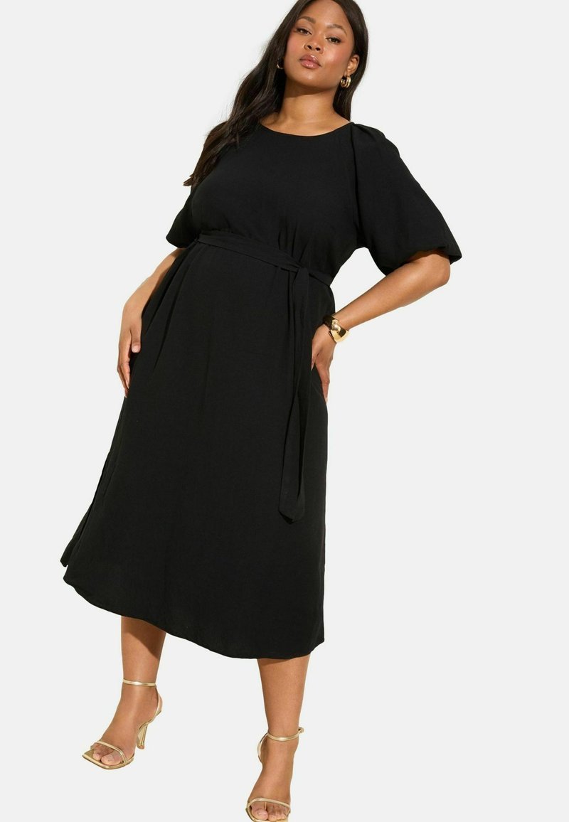 Schwarzes Midikleid mit rundem Ausschnitt, kurzen Puffärmeln und einem gebundenen Taillengürtel. Glatter Stoff mit einem fließenden Rock und seitlichen Schlitzen.