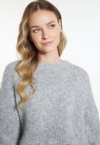Hellgrauer Strickpullover mit lockerer Passform, der über eine gerippte Textur und einen Rundhalssaum verfügt. Weicher Stoff mit gemütlichem Aussehen.