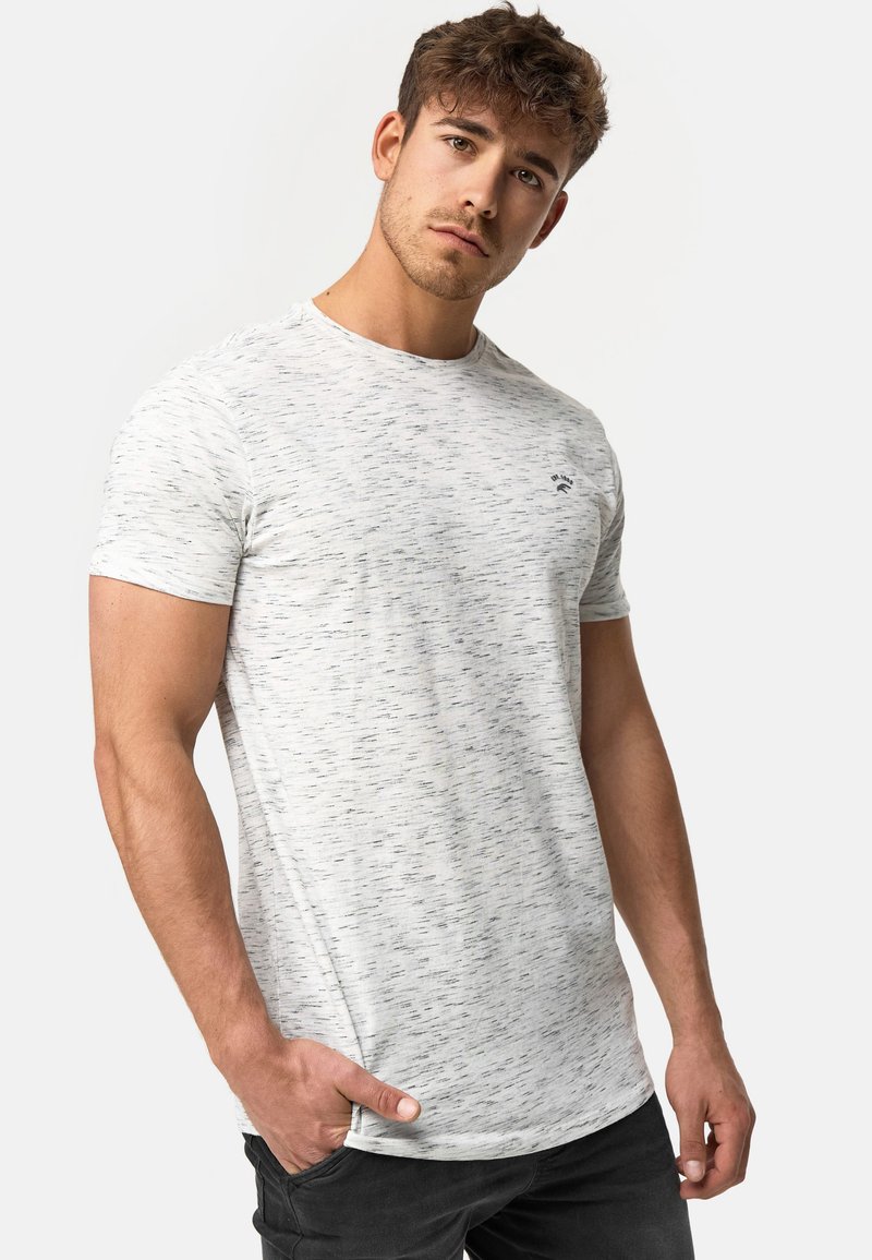 Jasnoszary t-shirt z krótkim rękawem o teksturowanym wzorze, okrągłym dekolcie i dyskretnym logo na piersi. W zestawie z ciemnymi spodniami.