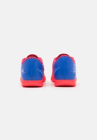 Scarpe da ginnastica blu e rosa con una tomaia in rete testurizzata, tacco curvo e suola in gomma con un motivo antiscivolo. Dettagli bianchi minimi.