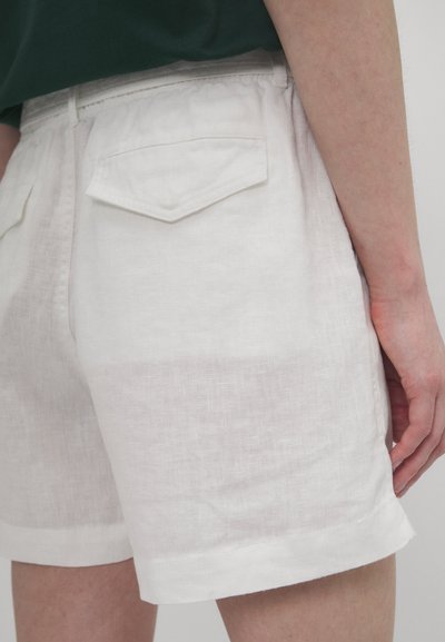 Hvite linshorts med en teksturert overflate, som har to baklommer og rullet kant. Stoffet ser lett og pustende ut.