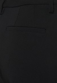 Svarta byxor med en strömlinjeformad design och mjuk textur. Inkluderar en bakficka och skräddarsydd sömnad för ett rent avslut.