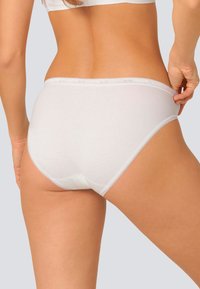 Slip in cotone bianco con una texture liscia, caratterizzato da un delicato bordo in pizzo in vita e un design classico a copertura totale.