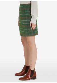 Vihreä ruudullinen tweed-hame, jossa ruskeat korostuslinjat. Yhdistetty ruskeisiin nahkaisiin nilkkureihin, joissa on joustavat sivupaneelit ja matalat korot.