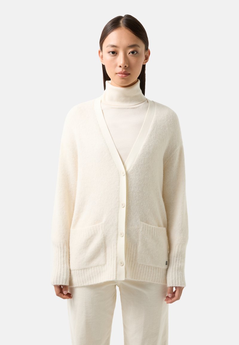 Cremfarbener Wollcardigan mit V-Ausschnitt, langen Ärmeln und gerippten Bündchen. Verfügt über zwei vordere Taschen und eine Knopfverschlusst. Weiche Textur.