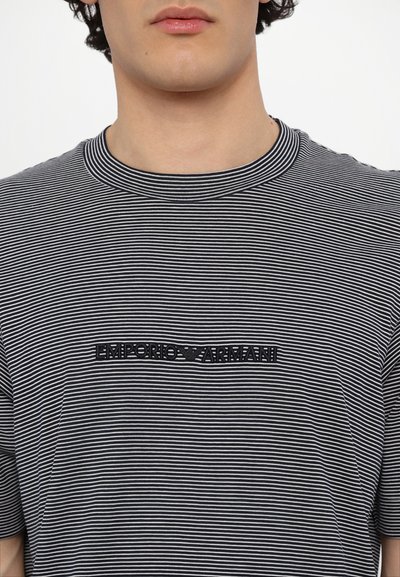 T-shirt às riscas pretas e brancas com decote redondo. Apresenta um logótipo bordado "Emporio Armani" centrado no peito. Material em algodão.