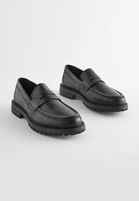Sorte læder loafers med en tekstureret rem, rund tå og en robust gummisål med dybe riller for greb.