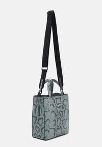 Kvadratisk väska med ett ljusblått mönster som efterliknar ormskinn. Har en svart justerbar rem och dubbla övre handtag för olika bäralternativ.