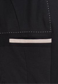 Tissu noir avec des détails de couture blanche et une poche fendue horizontale ornée d'une bordure beige clair.