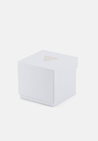 Boîte blanche texturée avec un emblème triangulaire et des accents dorés, dotée d'un couvercle et d'un design épuré et minimaliste.