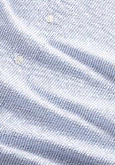 Jasnoniebieska i biała tkanina w paski z dwoma białymi guzikami, pokazująca fakturę i miękkie fałdy.