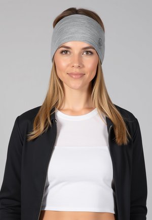 Grijze stoffen hoofdband met een gladde textuur, voorzien van een subtiel logo detail. Gedragen met een wit topje en een zwarte jas.