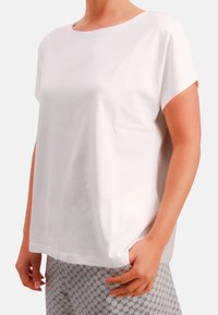 White short-sleeve t-shirt in soft cotton, featuring a round neckline and subtle logo detail on the chest. Paired with patterned pants.