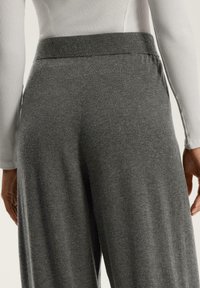 Grå, stretchiga byxor med en mjuk textur och vida ben, med ett högt elastiskt midjeband. Lämpliga för vardagsbruk eller avkoppling.