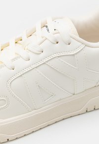 Weißer Ledersneaker mit strukturierter Oberfläche, präsentiert das auffällige "AX"-Logo-Design, runde Schnürsenkel und eine Gummisohle.