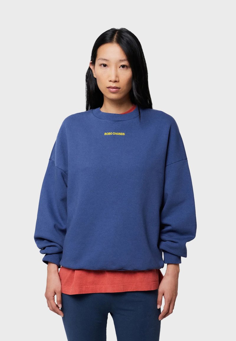 Blå tröja med avslappnad passform, ribbad halsringning och muddade ärmar. Har gul "BOBO CHOSES"-brodyr på bröstet.