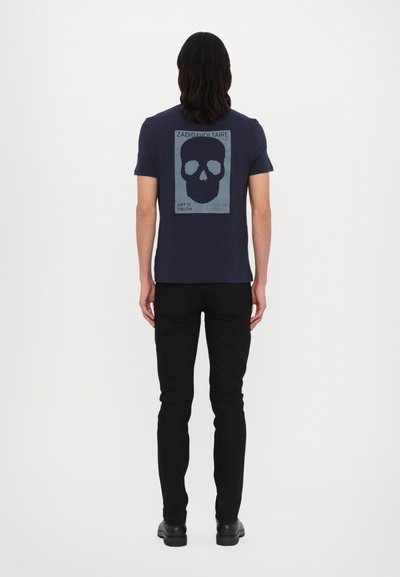 Camisa de color azul marino hecha de tejido suave, con un gran gráfico de calavera en la parte posterior en azul claro, y un texto debajo que dice "EL ARTE ES VERDAD."