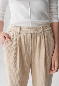 Beige Corduroyhosen mit vertikalen Rippungen, elastischem Bund und Taschen, im lässigen Schnitt und aus weichem Material.