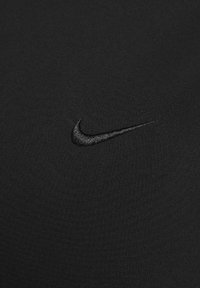 Zwart sportshirt met een gladde textuur, met een klein, geborduurd zwart Nike-logo aan de linkerkant.