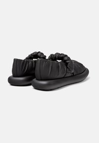 Černé nadýchané boty na slip-on s nařaseným textilním svrškem, kulatou špičkou a silnou gumovou podrážkou. Texturovaný materiál s hladkým povrchem.