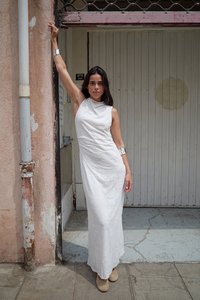 Valkoinen maksimekko, jossa on laskostettu kaula-aukko, kukkakuosiset pinnat ja hihattomat mallit. Hopeiset käsikoruja täydentävät asua. Vapaamuotoiset kengät näkyvät.