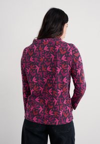 Figurbetontes Langarmoberteil in Dunkelpurpur mit einem Blattmuster in Pink- und Rottönen. Weicher Stoff, runder Ausschnitt und nahtloses Design.