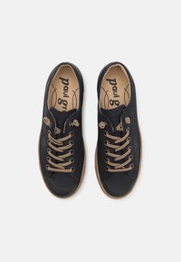 Tengeri kék vászon sportcipő barna fűzővel, kerek orral, gumitalppal és diszkrét logóval a talpbetéten. Fűzőlyukak és varrás részletek az oldalán.