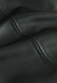 Sort struktureret læder med synlige sømme, der viser en glat overflade og subtil glans, hvilket skaber et rigt, taktilt udseende.