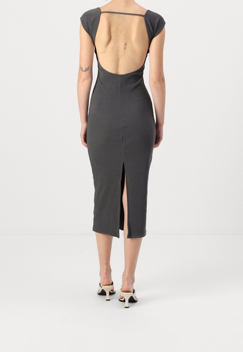 Šedé upnuté šaty s krátkými rukávy, otevřeným zády, postranním rozparkem a hladkou texturou. Tkanina se přizpůsobuje tělu a vytváří elegantní siluetu.