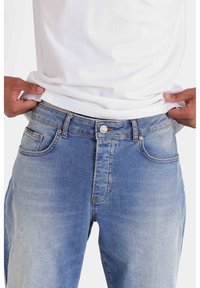 Jeans in denim blu chiaro con taglio dritto, dotati di chiusura a bottone, tasche frontali e leggere scoloriture per un aspetto vissuto.