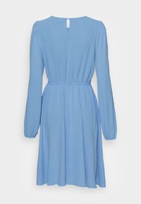 Vestido longo de mangas compridas azul claro com cintura franzida, decote arredondado e detalhe de abertura nas costas. Tecido macio e texturizado com uma silhueta fluida.