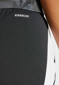 Shorts atletici negri cu un brâu texturat, accent alb pe laterale și logo-ul "AEROREADY" în litere albe pe față.