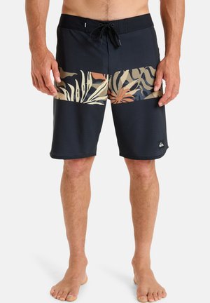 Schwarze Badeshorts mit einem strukturierten diagonalen Muster. Mit einem mehrfarbigen Blumenmuster auf der Vorderseite und einem Kordelzugbund.
