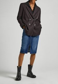 Mustat kaksiriviset bleiseri hopeanvärisillä napilla, yhdistettynä farkkukynähameeseen. Mallilla on päällään mustat nilkkurit, joissa on tekstuuripohjat.